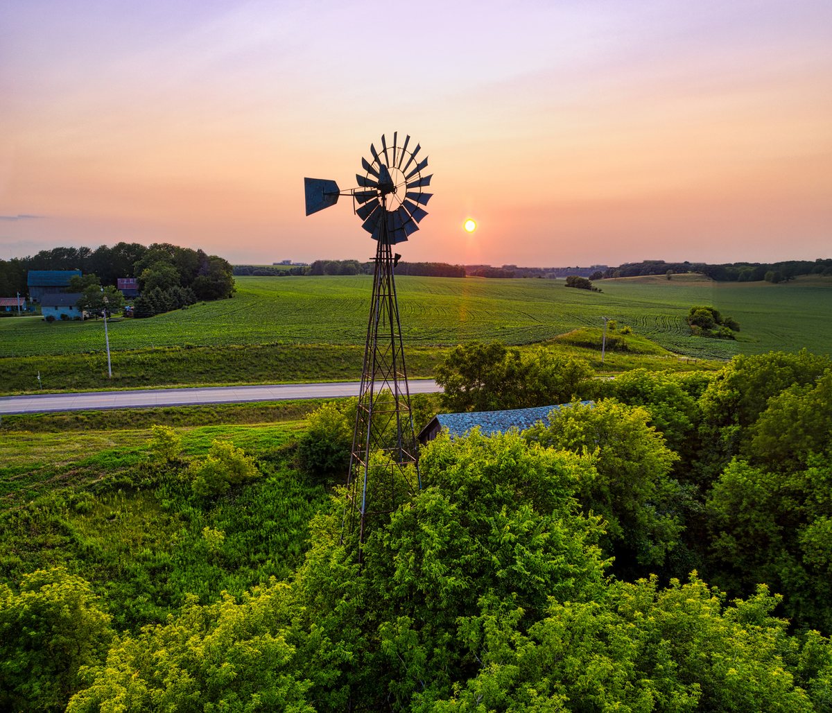 A windmill turning over open Texas farmland at sundown