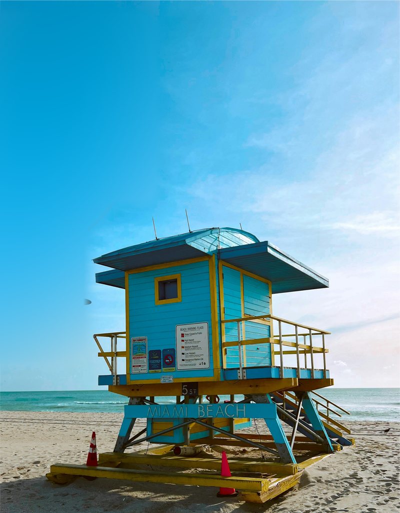 A blue and yellow lifeguard tower on Miami Beach in the late afternoon sun