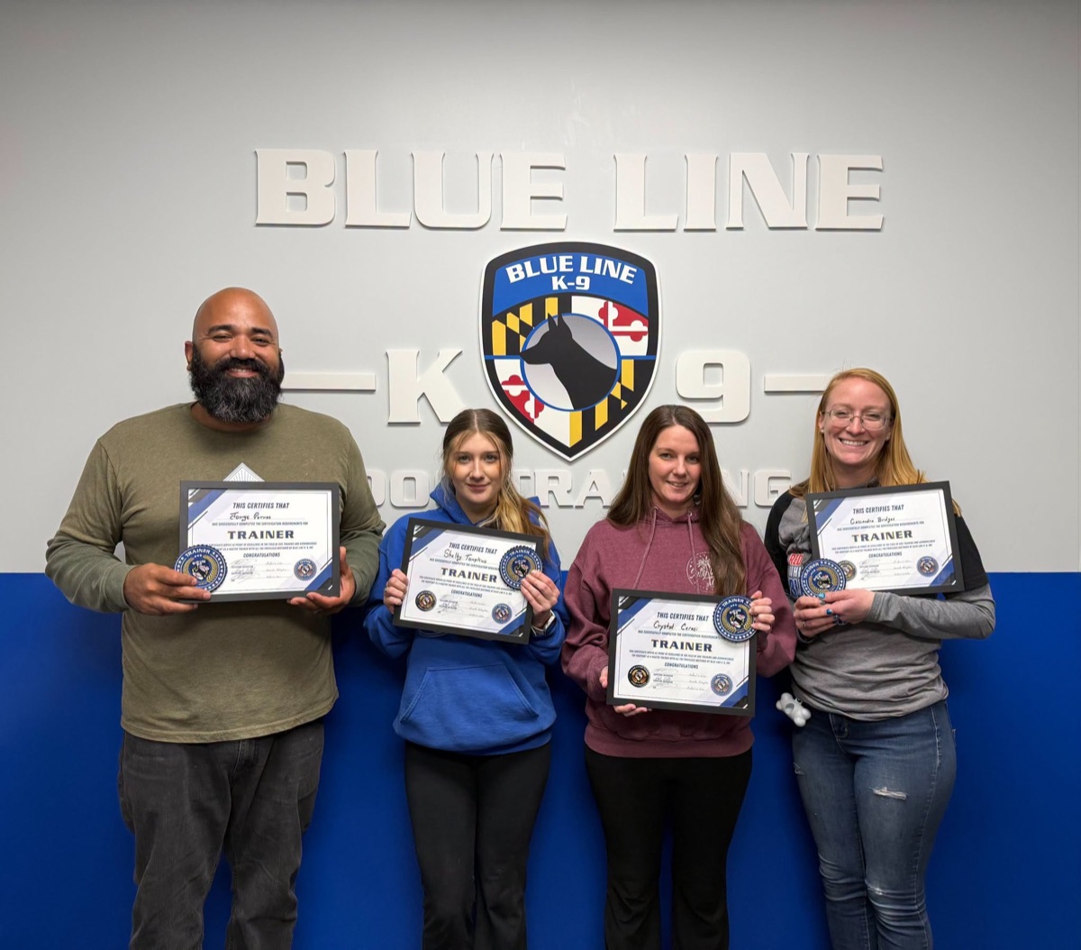 Four Blue Line K-9 Trainer Academy graduates holding their trainer certificates